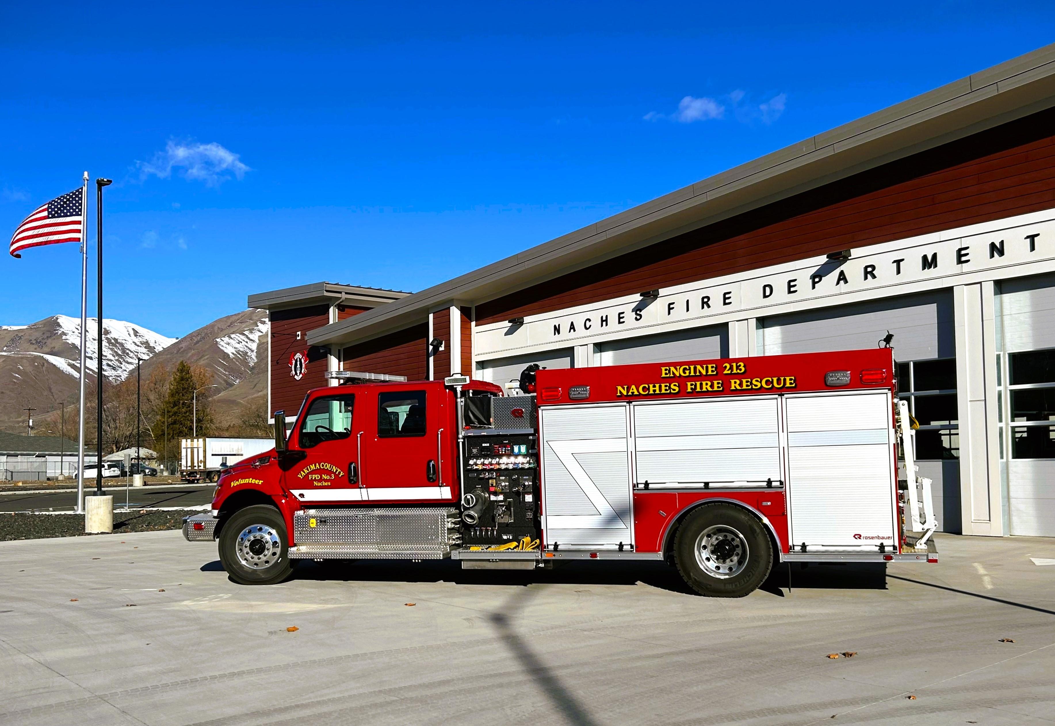 Fire engine in front of fire department building with blue sky above