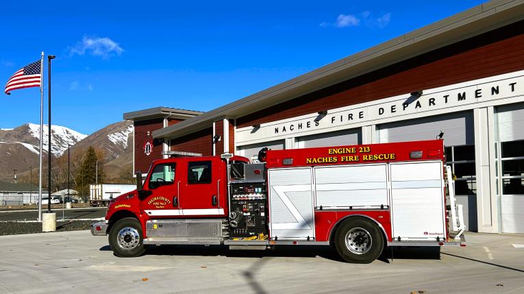 Fire engine in front of fire department building with blue sky above